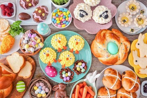 Easter table scene with an assortment of breads, desserts and treats. Top view over a wood background. Spring holiday food concept.