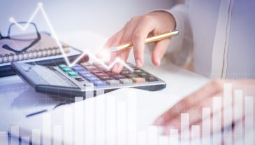 Accountant calculating profit with financial analysis graphs. Notebook, glasses and calculator lying on desk. Accountancy concept. Cropped view.