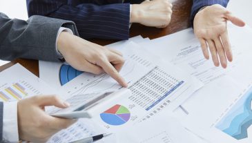 Two businessmen in elegant suits at a business meeting making calculations in the office