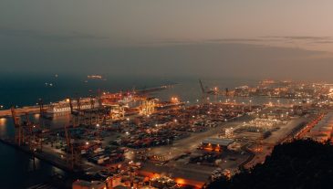 A distant shot of a port with boats loaded with cargo and shipment during nighttime